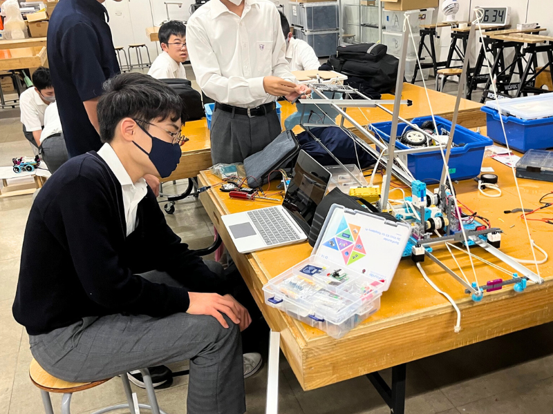 PC片手にロボットを真剣に見つめる様子